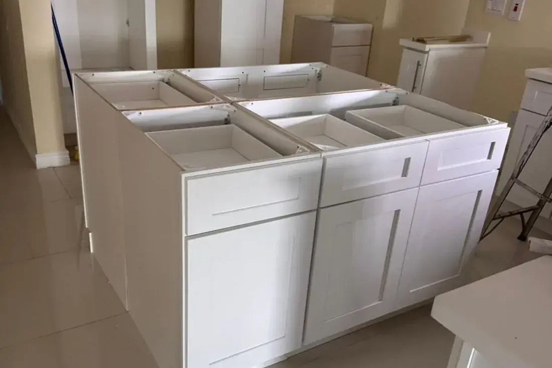 White base units and island carcasses set out on a tiled floor, no counters yet