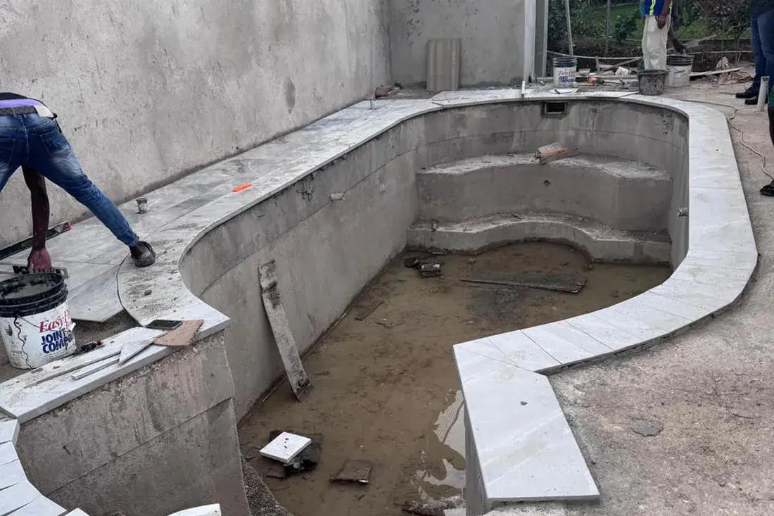 A bare concrete pool shell with the steps formed, before tiling and coping