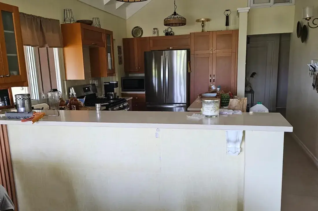 A plain painted kitchen counter front in an open plan room under a vaulted ceiling