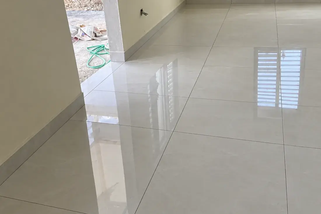 The same room fully tiled and grouted, a polished floor running unbroken to the skirting