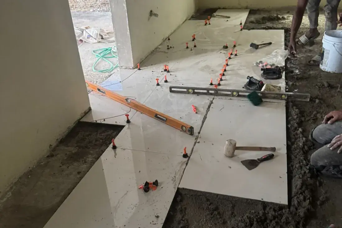 Large format tiles part laid on a bare screed with levelling clips and adhesive out on the floor