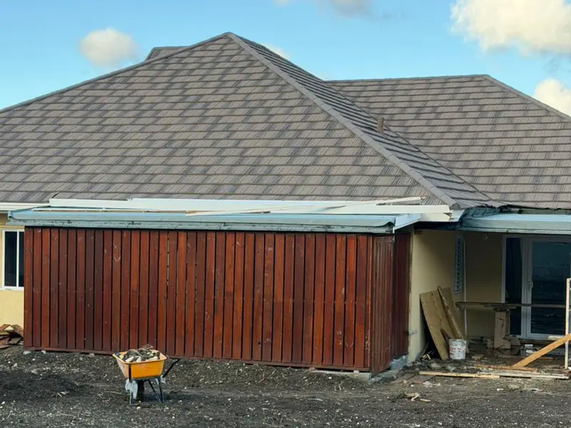 A timber clad end wall stained dark red under a finished shingled roof