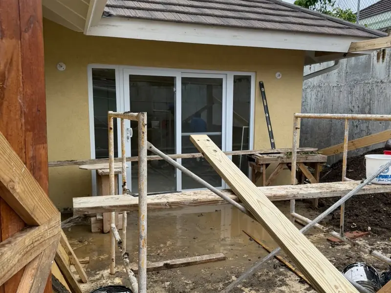 Timber formwork and props in place for an addition alongside a finished rendered wall