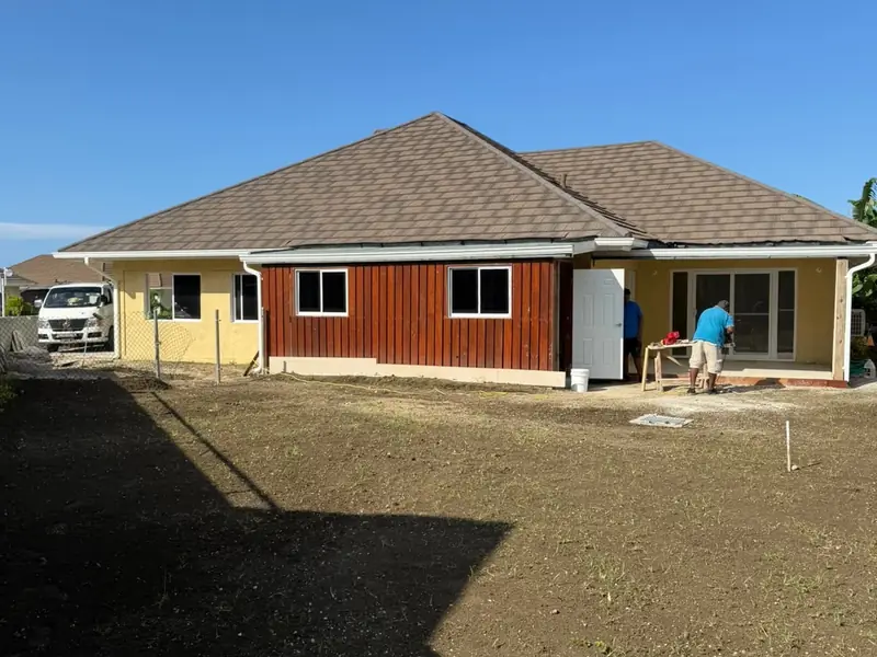 A finished house with timber cladding and dark graded earth across the driveway