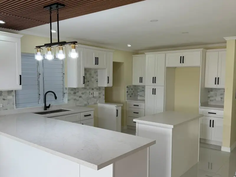 A white kitchen with a large island, mosaic splashback and a timber slatted ceiling above