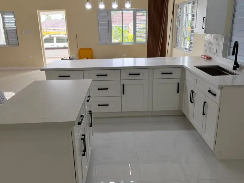 An L shaped white kitchen with a polished tiled floor and an exposed timber beam