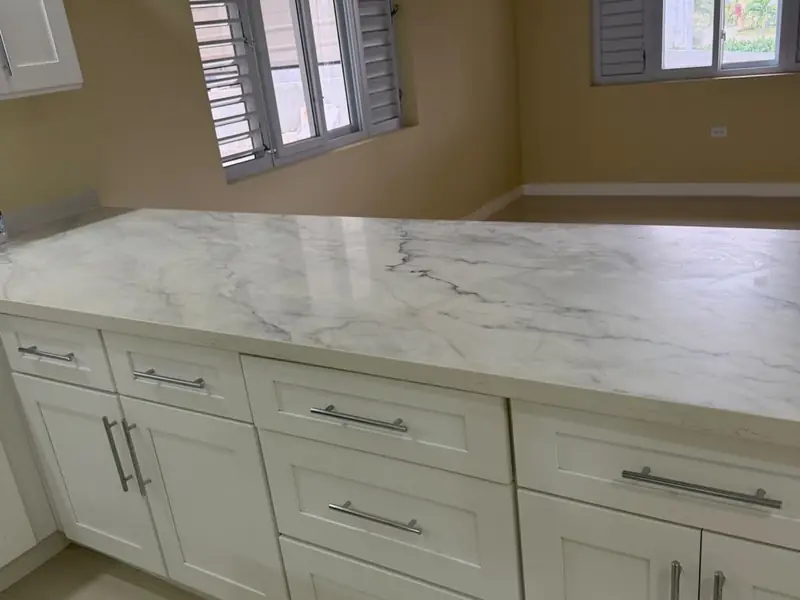 A run of shaker style base units with a marble counter and shuttered windows above