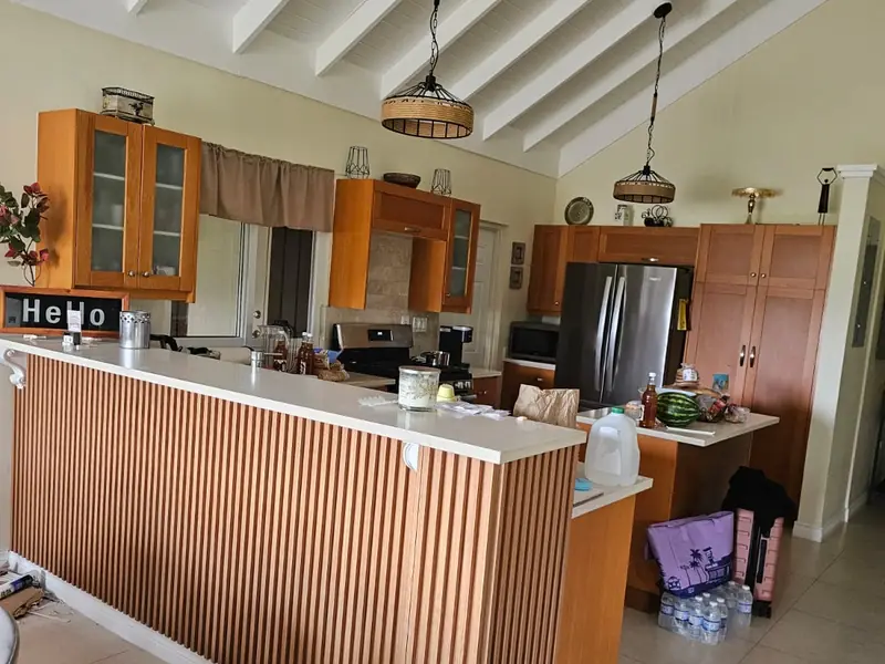 An open plan kitchen with a timber slat counter front under a white vaulted ceiling