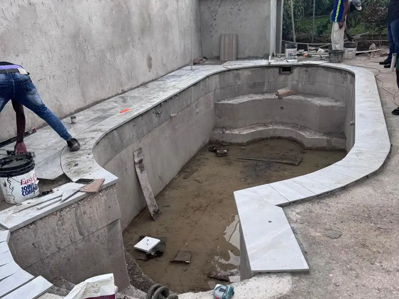 A bare concrete pool shell with the steps formed, before tiling and coping