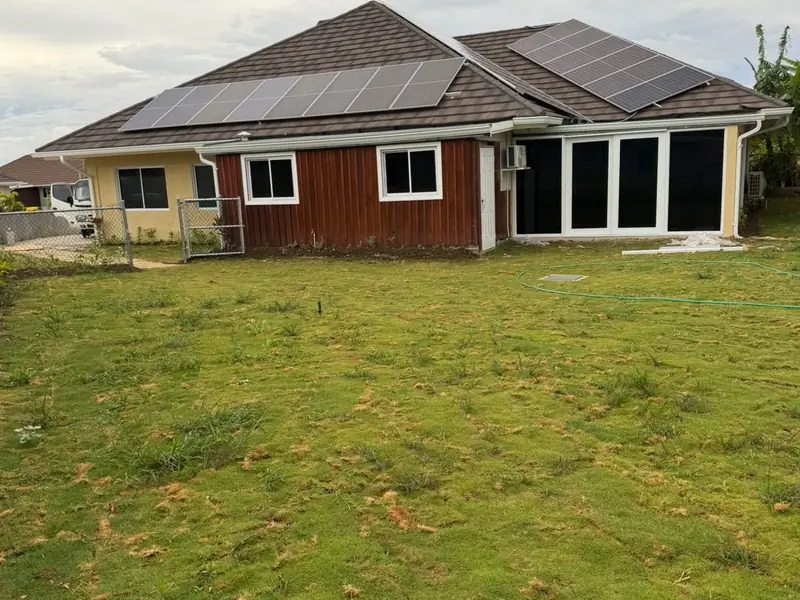 The rear of a finished house with timber cladding and render, glazed doors and a lawn