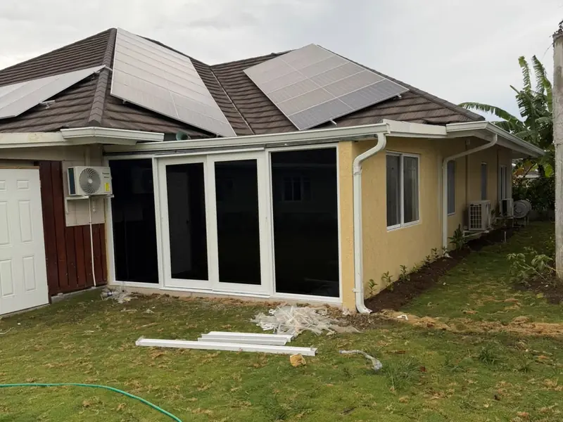 The rear of a finished house with solar panels on the roof, timber cladding and a laid lawn