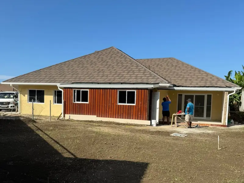The same house with the hipped roof fully decked, shingled and the eaves closed in