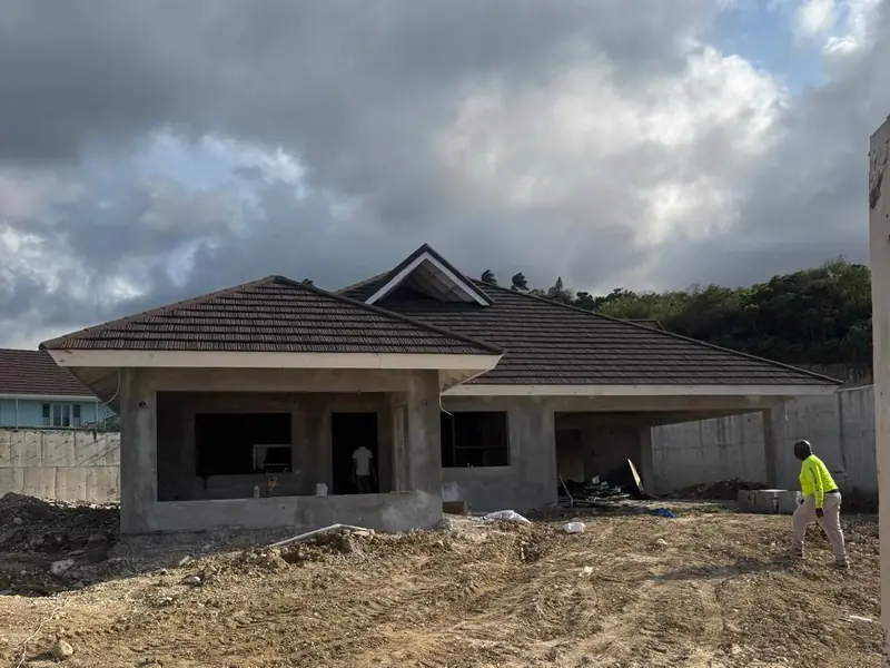 A house at block and roof stage, bare concrete with no windows and the ground still raw
