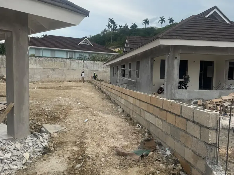 A narrow strip of site between a new block retaining wall and houses under construction