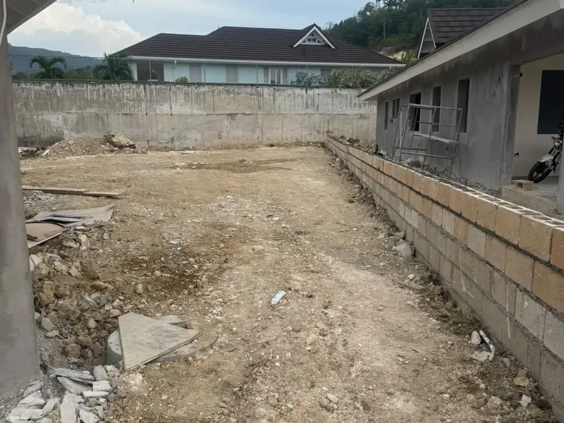 Excavated ground between a block retaining wall and a house under construction