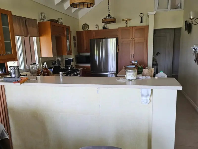 A kitchen counter front in plain paint, in an open plan room under a vaulted ceiling