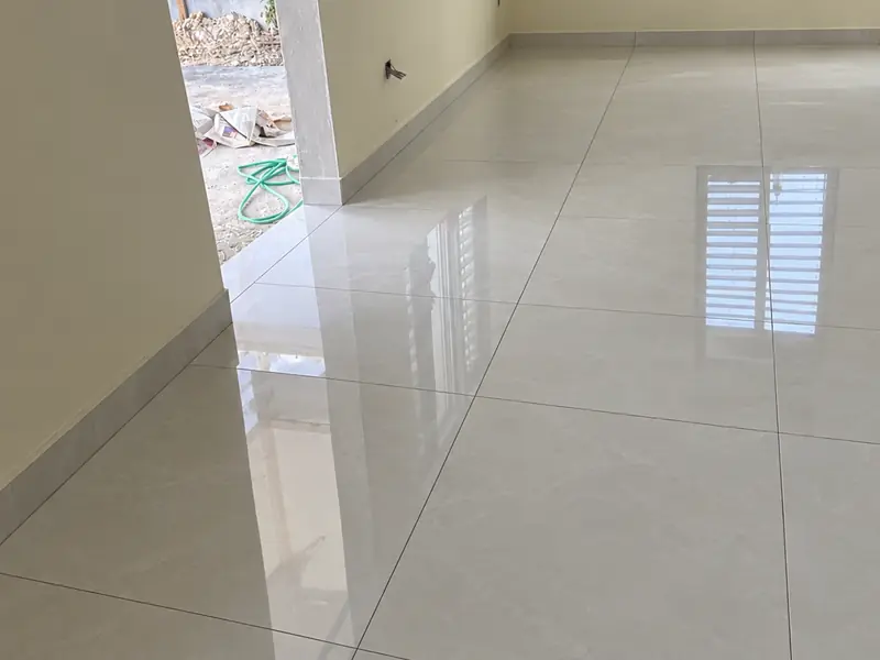 The same room fully tiled and grouted, a polished floor running unbroken to the skirting