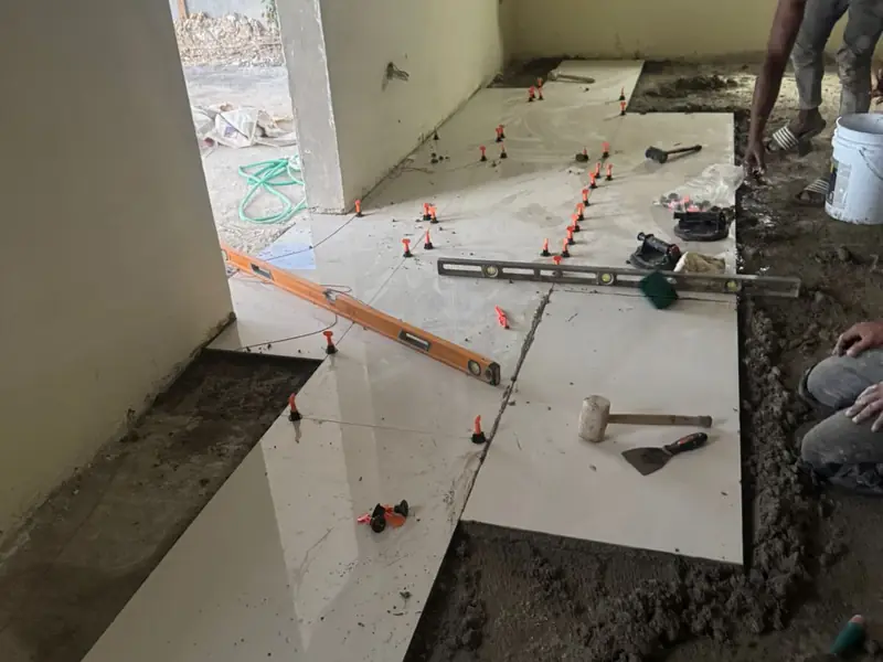 Large format tiles part laid on a bare screed with levelling clips and adhesive out on the floor
