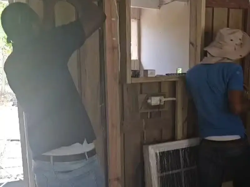 A worker fitting and checking a timber door frame inside a finished room