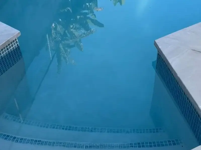A slow pan across a finished swimming pool with a marble tiled surround