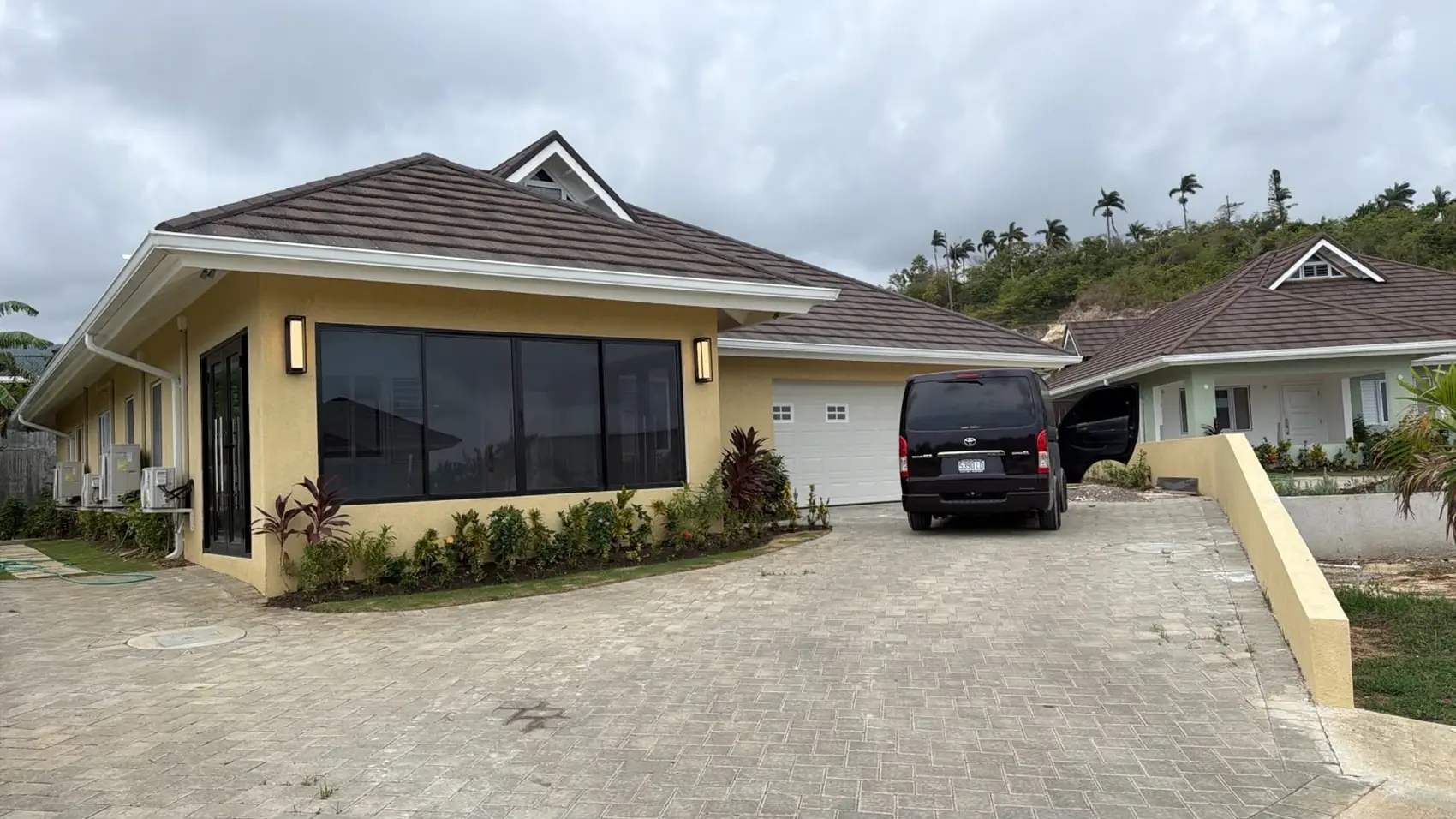 A completed Max Team house with a hipped roof, paved driveway and landscaped front