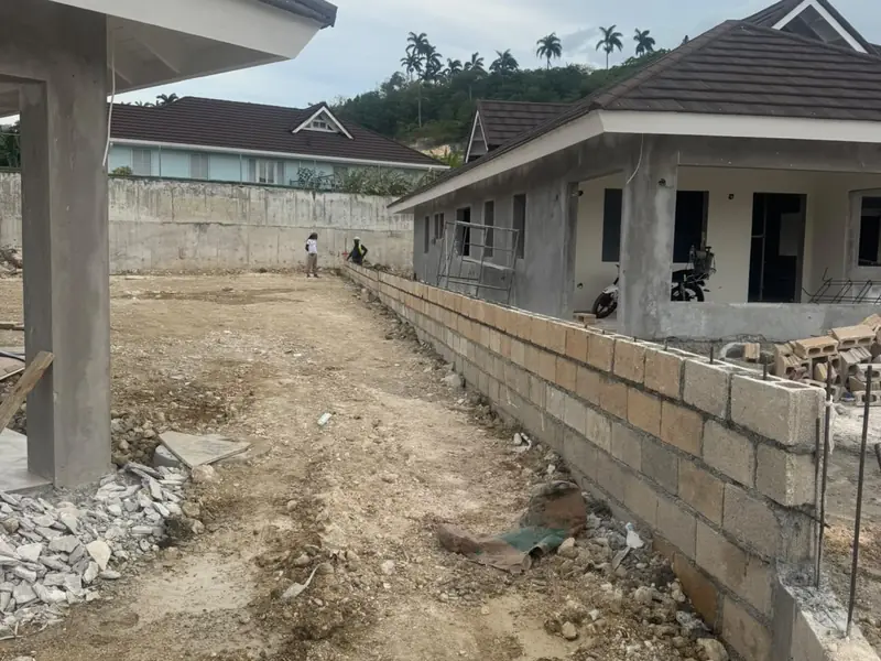 Houses under construction on a terraced site behind a block retaining wall