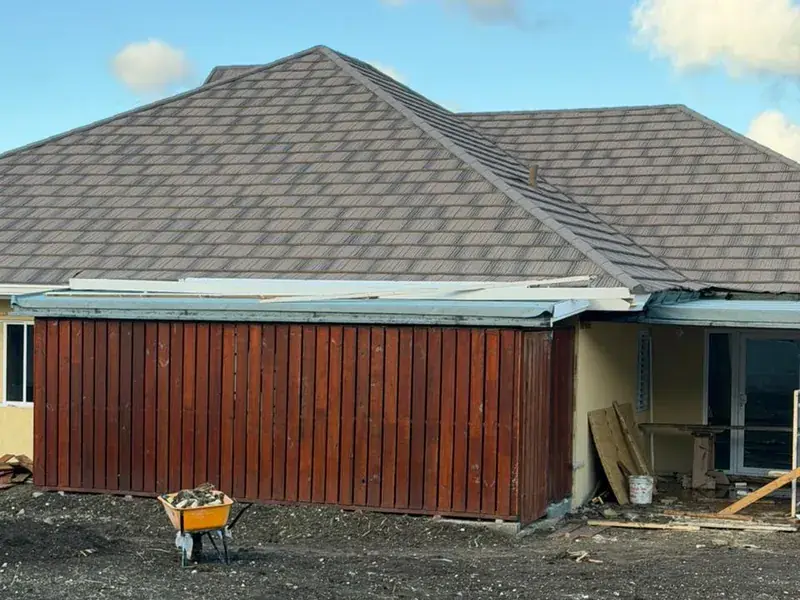 A timber clad end wall stained dark red, under a finished shingled roof