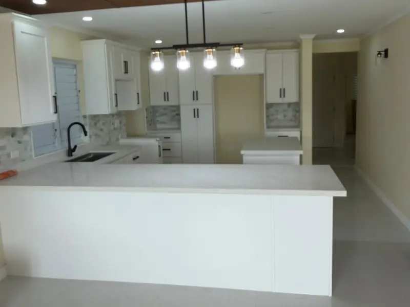 A kitchen island with a marble worktop, gas range and wall ovens
