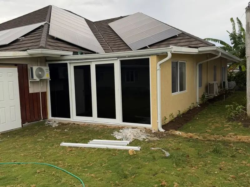 The rear of a finished house with full height patio doors onto a lawn