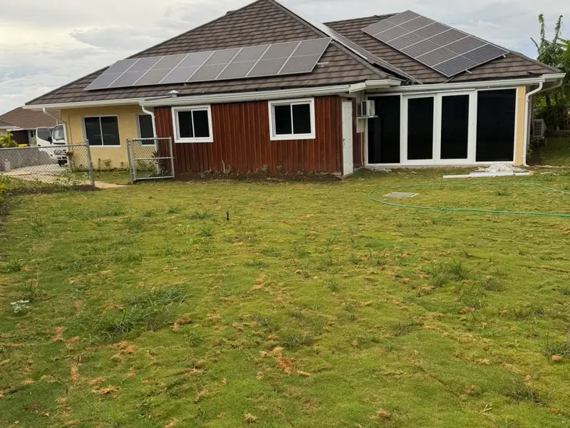 The rear of a finished house with solar panels on the roof and a laid lawn
