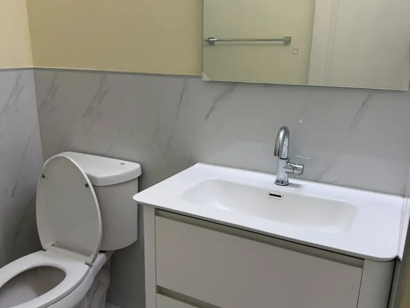 A cloakroom with a wall hung vanity, marble splashback and a toilet