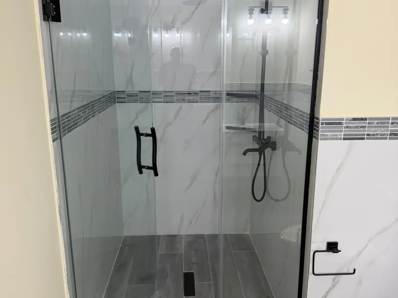 A finished walk in shower with large format tiling and black fittings