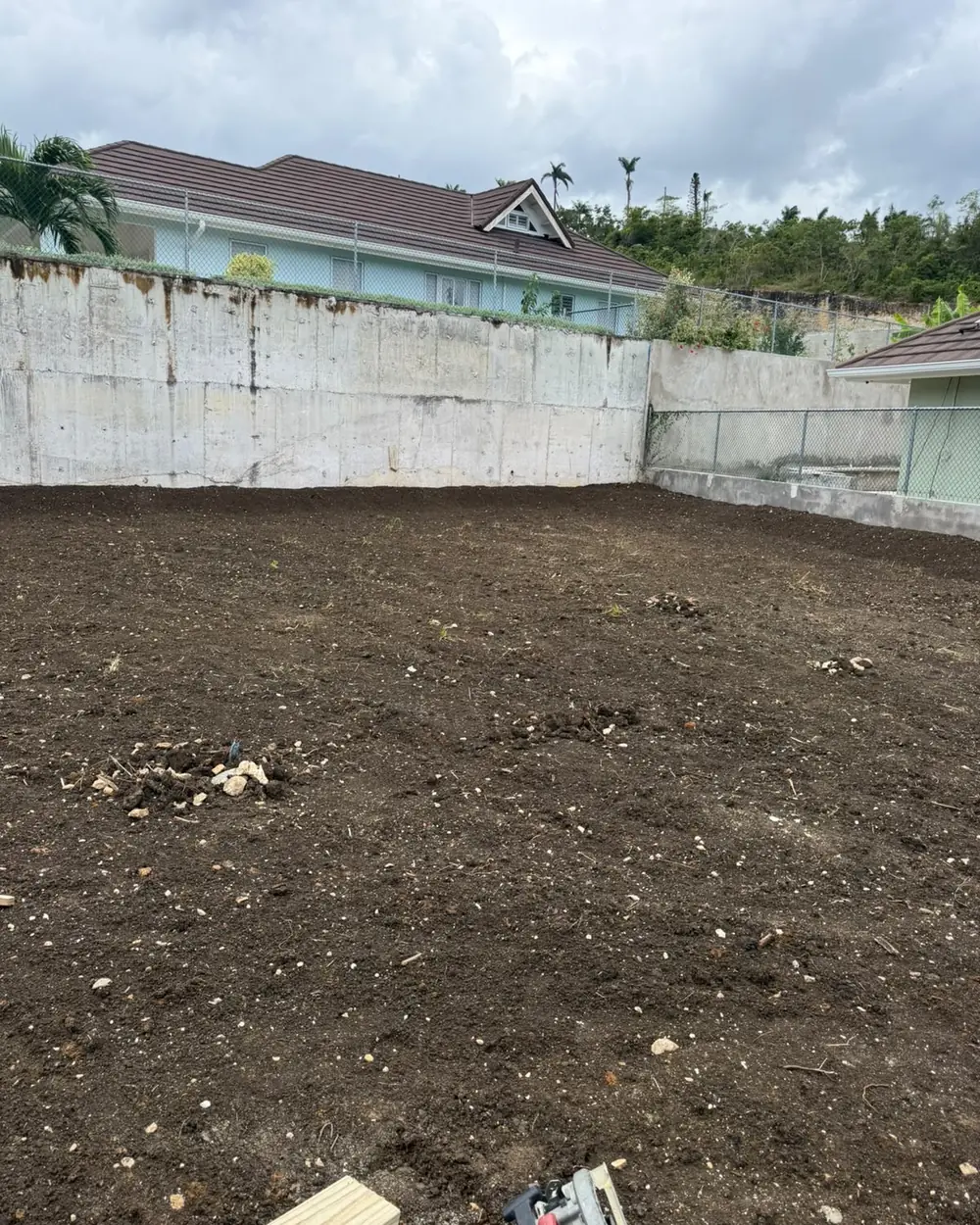 A cleared and levelled plot behind a new block retaining wall, ready for foundations